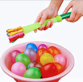 Colorful balloon pump being used to inflate balloons in a pink bowl.