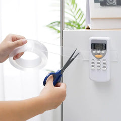 Person cutting a strip of tape with scissors near an electronic device