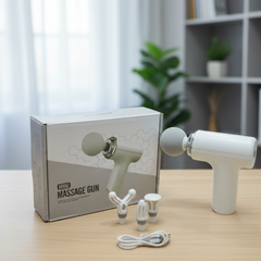White mini massage gun with accessories on a table next to its packaging.