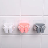 Three plastic holders in white, pink, and gray on a tiled wall.