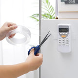 Person cutting a strip of tape with scissors near an electronic device