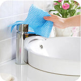 Hand cleaning a faucet with a blue chevron patterned cloth, with a white sink and tiled wall in the background.