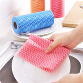 Pink and blue cleaning cloths on a kitchen sink with a hand holding a pink cloth.
