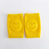 Pair of yellow knee pads with smiley face designs on a white background