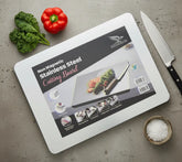 White cutting board with product information on a gray surface with vegetables and a knife.