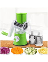 Green manual vegetable spiralizer with attached blades on a wooden surface, surrounded by sliced vegetables.