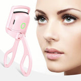 Pink eyelash curler next to a close-up of a woman's face with long eyelashes.