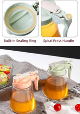 Glass bottle with spiral press handle and built-in sealing ring, filled with a yellow liquid on a white surface.