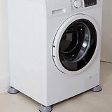 A white front-loading washing machine with gray feet, shown in a clean indoor setting with a light beige wall and floor.