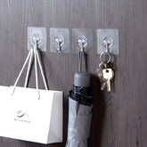 Clear hooks attached to a wooden wall with a bag, umbrella, and keys hanging from them.