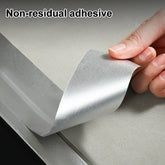 Roll of non-residual adhesive tape with a hand holding it, on a neutral background.