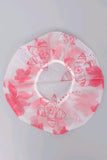 A circular white shower cap with a pink floral pattern, laid flat on a light gray background.