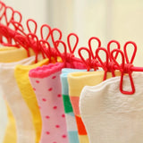 Colorful baby socks on red hangers against a neutral background