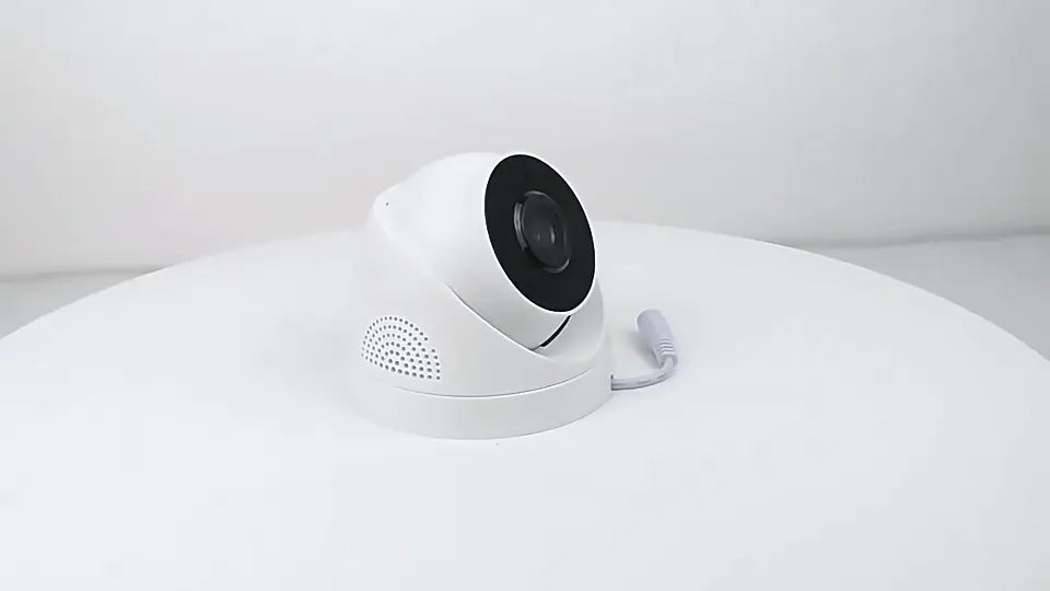 White security camera on a white surface with a light gray background
