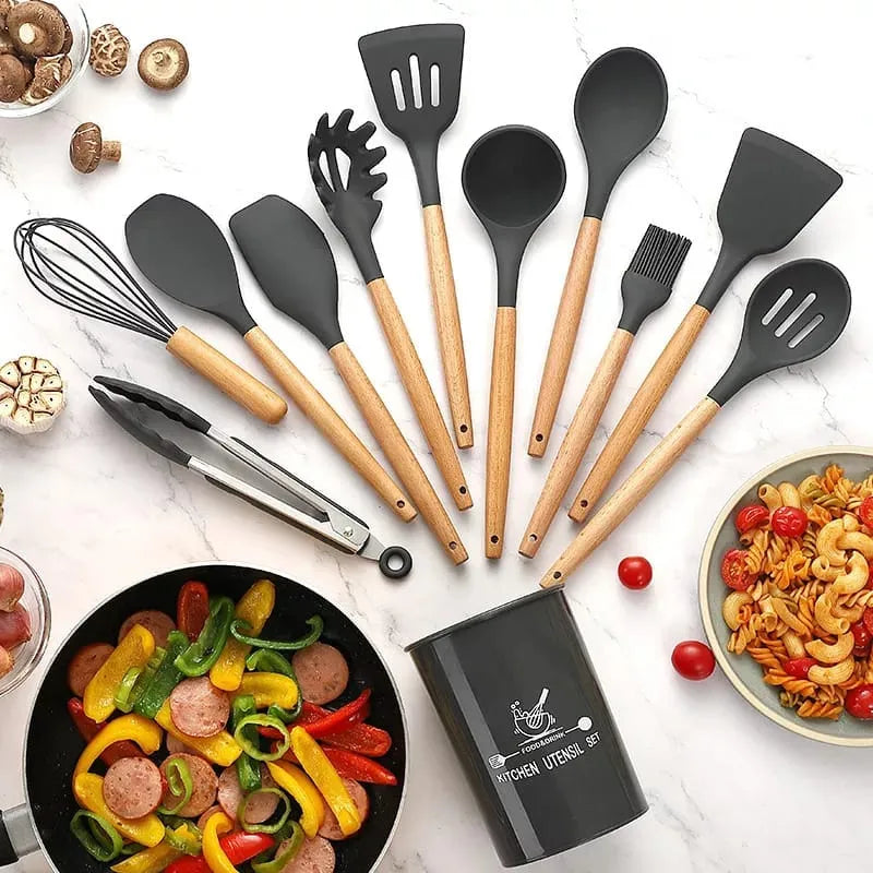 Set of kitchen utensils with wooden handles on a white surface with food items.