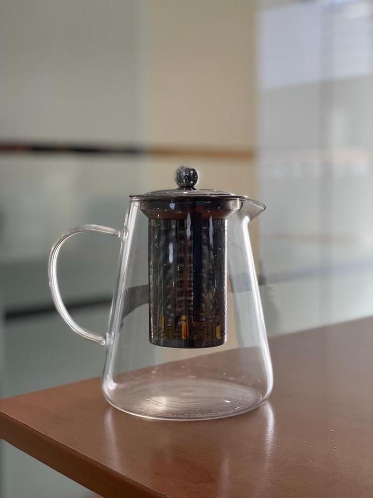 Clear glass teapot with metal lid on a wooden surface