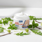 Jar of lipoma removal cream surrounded by green leaves on a white background