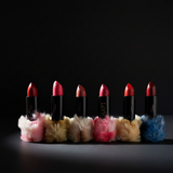 Set of six lipsticks with colorful feathered stands on a black background