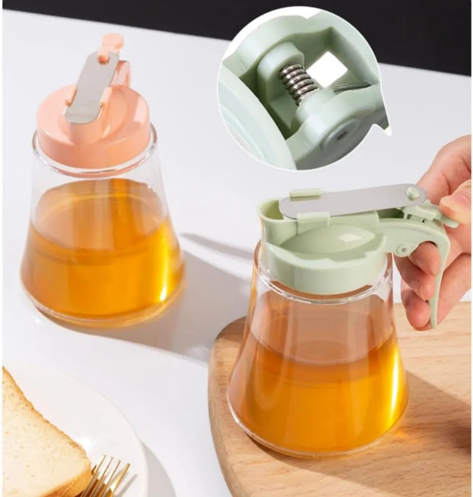 Glass container with a honey dipper on a white surface, with a close-up of the honey dipper.