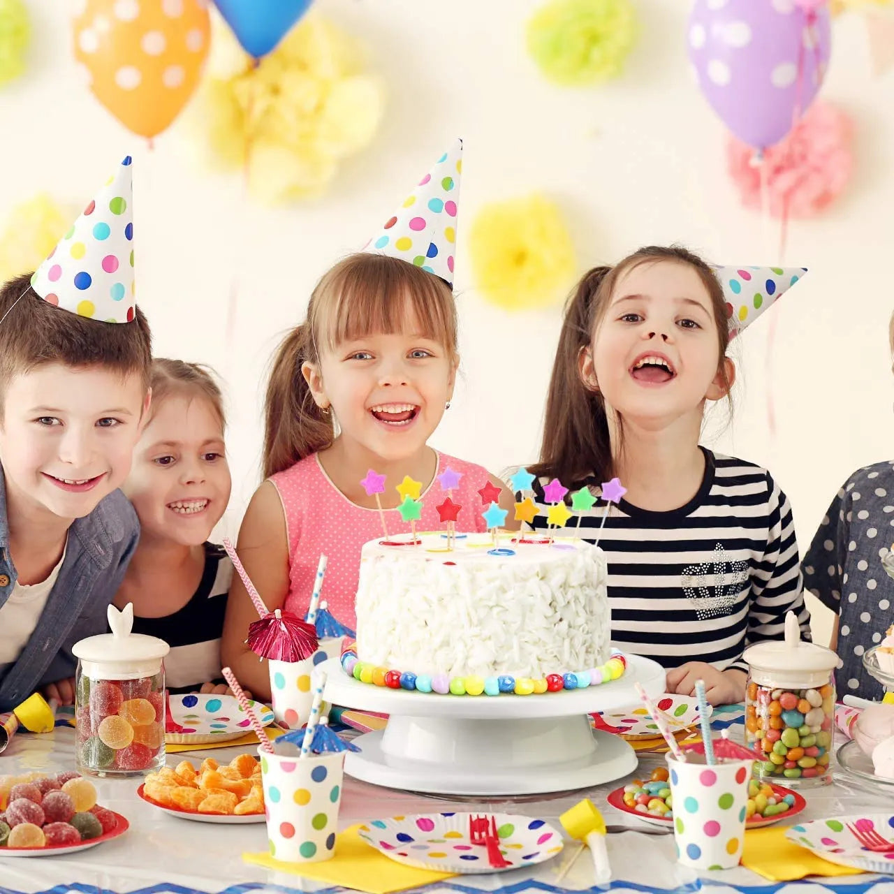 Children at a birthday party with a cake and balloons