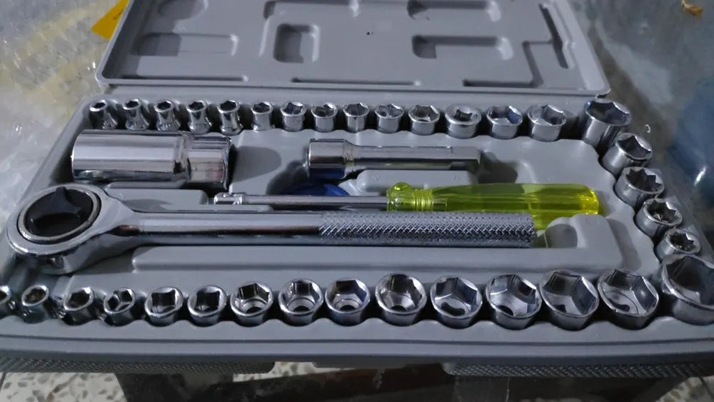 Set of tools including sockets and wrenches in a gray case.