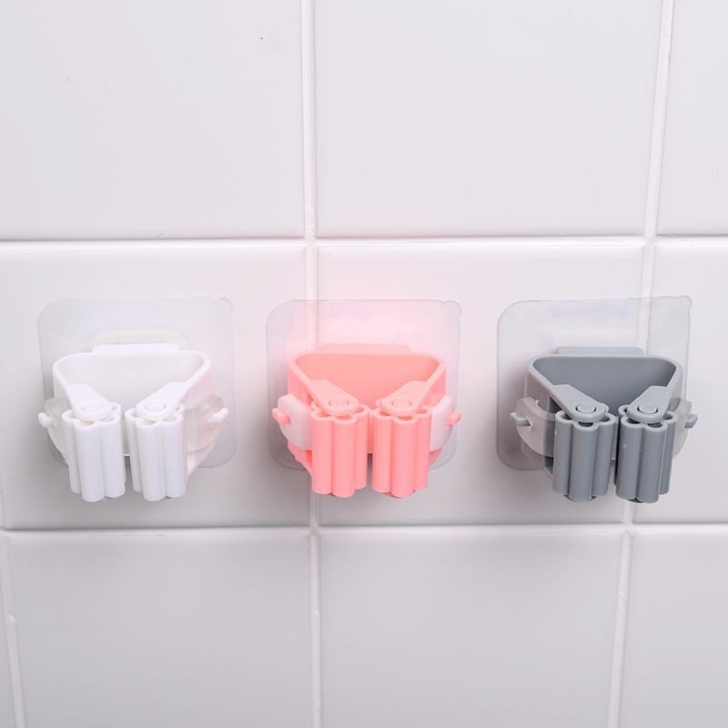 Three plastic holders in white, pink, and gray on a tiled wall.