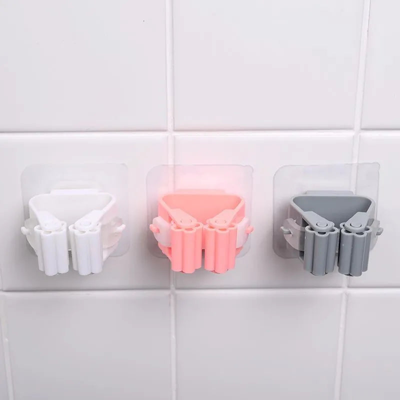 Three wall-mounted plastic holders in white, pink, and gray on a tiled wall.