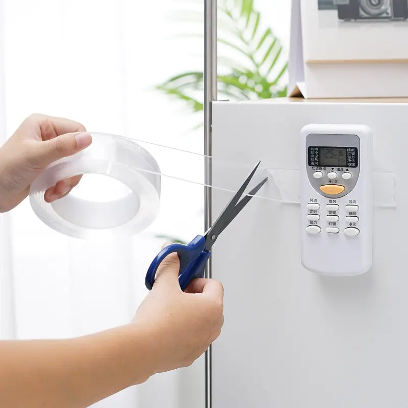 Person cutting a strip of tape with scissors near an electronic device