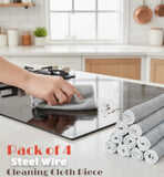 Person cleaning a stove top with steel wire cleaning cloth and multiple rolls of the same on a kitchen counter.