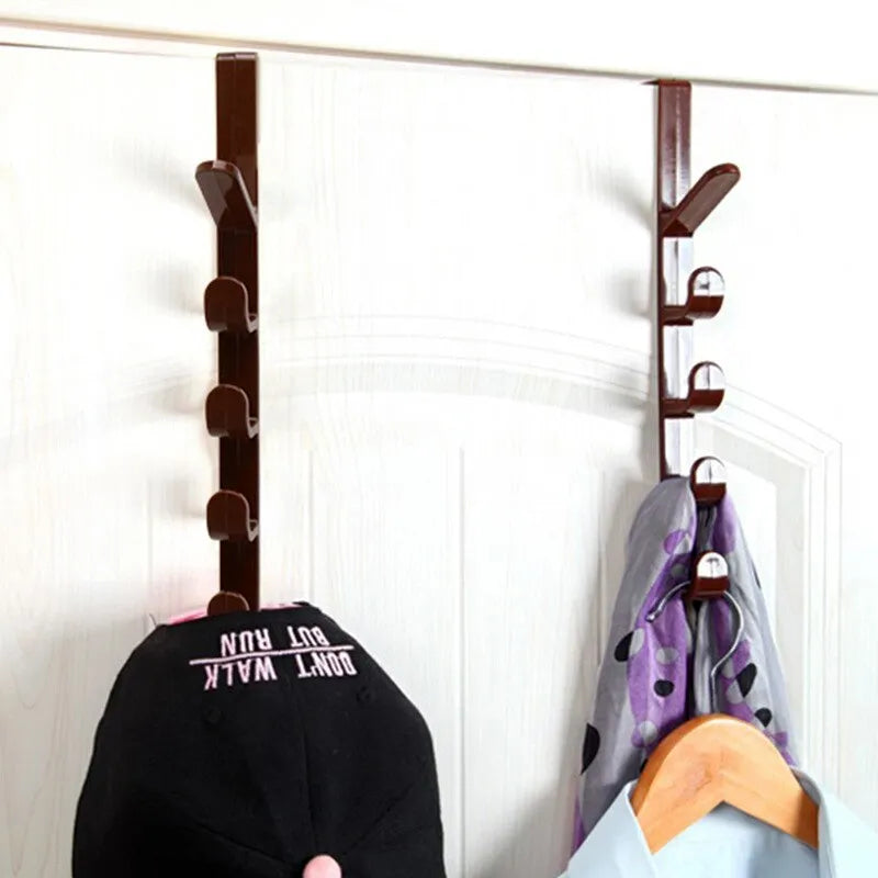 Wall-mounted coat rack with multiple hooks holding a black cap, purple jacket, and other items against a white wall.