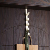 White wall hook with a brown paper bag and green fabric hanging on it against a wooden background
