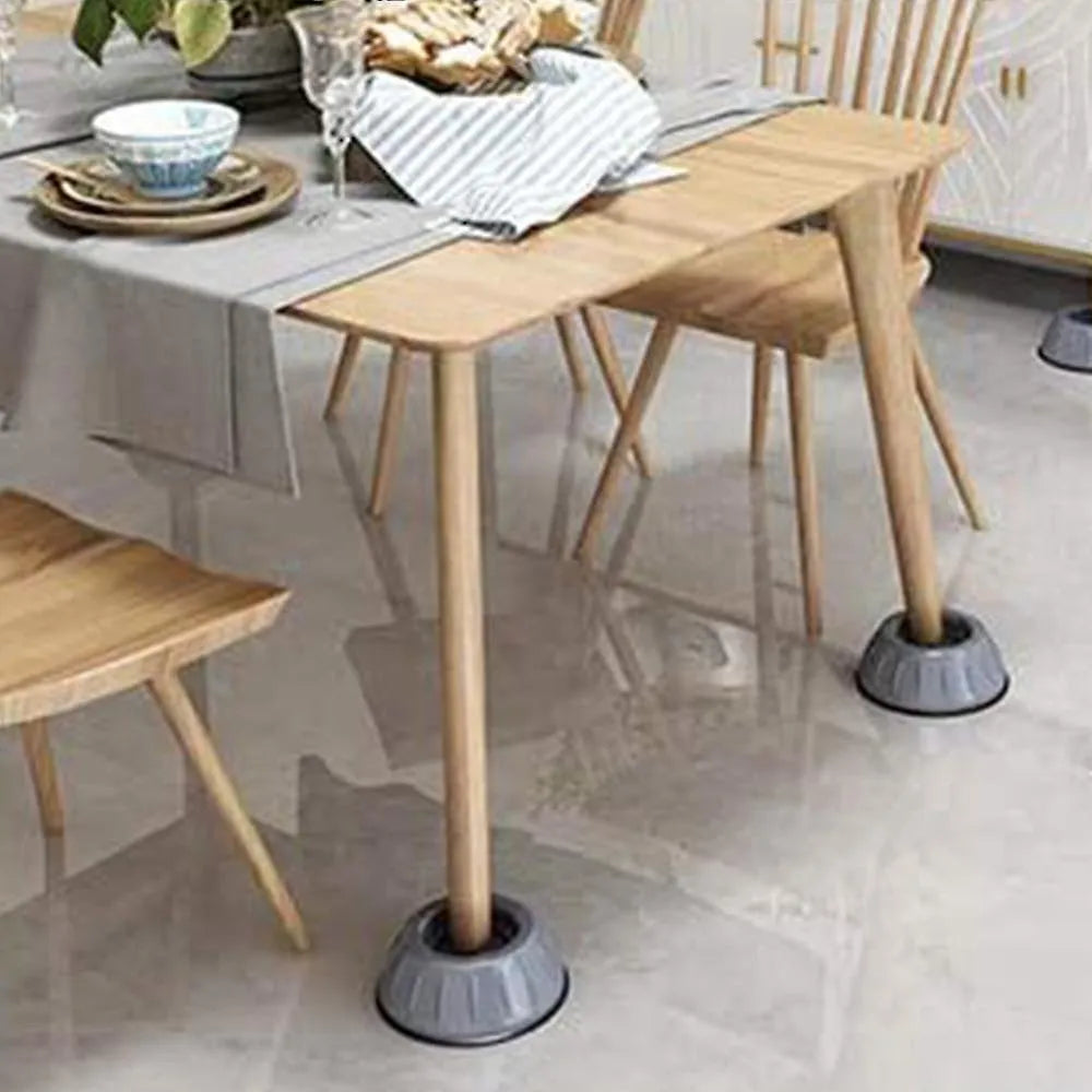 A wooden dining table with matching chairs in a bright indoor room, featuring gray suction-cup feet on the table legs to prevent sliding on a glossy tiled floor.