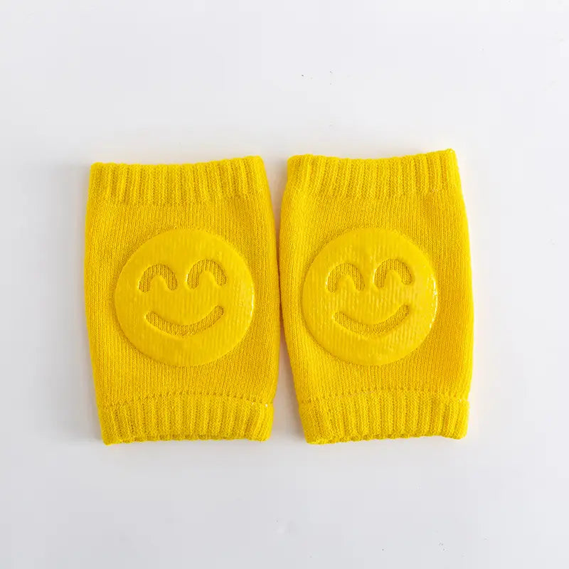 Pair of yellow knee pads with smiley face designs on a white background