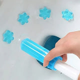 A hand holding a blue and white plastic syringe-like tool over a white sink, with several translucent blue flower-shaped pieces floating nearby.