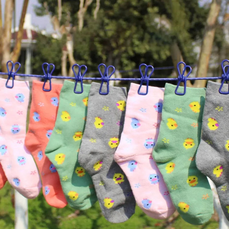 Colorful socks with patterns hanging on a clothesline outdoors.