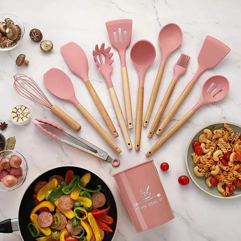 Pink kitchen utensils set on a marble surface with food items.
