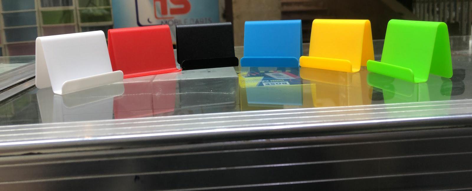 Colorful phone stands on a reflective surface with a blurred background