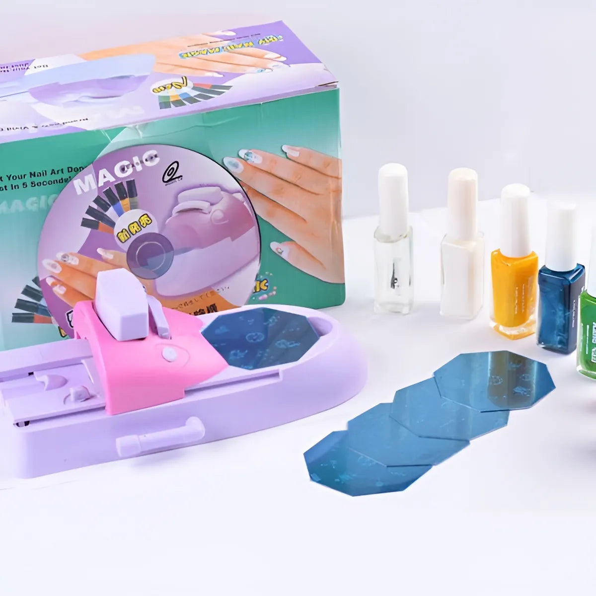 A nail art kit displayed on a white surface, including a pink and lavender nail drill machine, a CD, several nail polish bottles in white, orange, yellow, and blue, and blue hexagonal nail stickers.