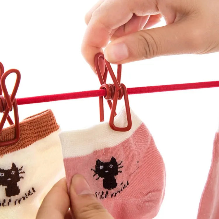 Person hanging a pink sock with a black cat design on a red clothesline.
