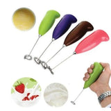 Four handheld electric milk frothers with colorful handles in green, purple, brown, and pink, shown with metal mixing wires and small circular usage insets on a white background. A hand is holding one green frother in the lower right corner.