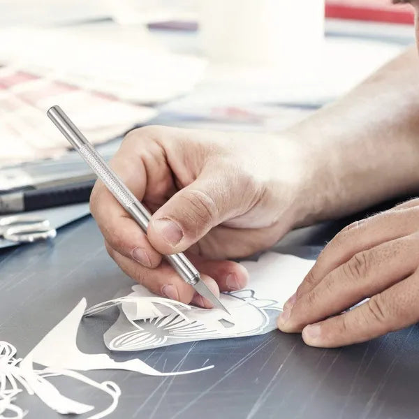 Person cutting out paper butterfly shapes with scissors on a table.