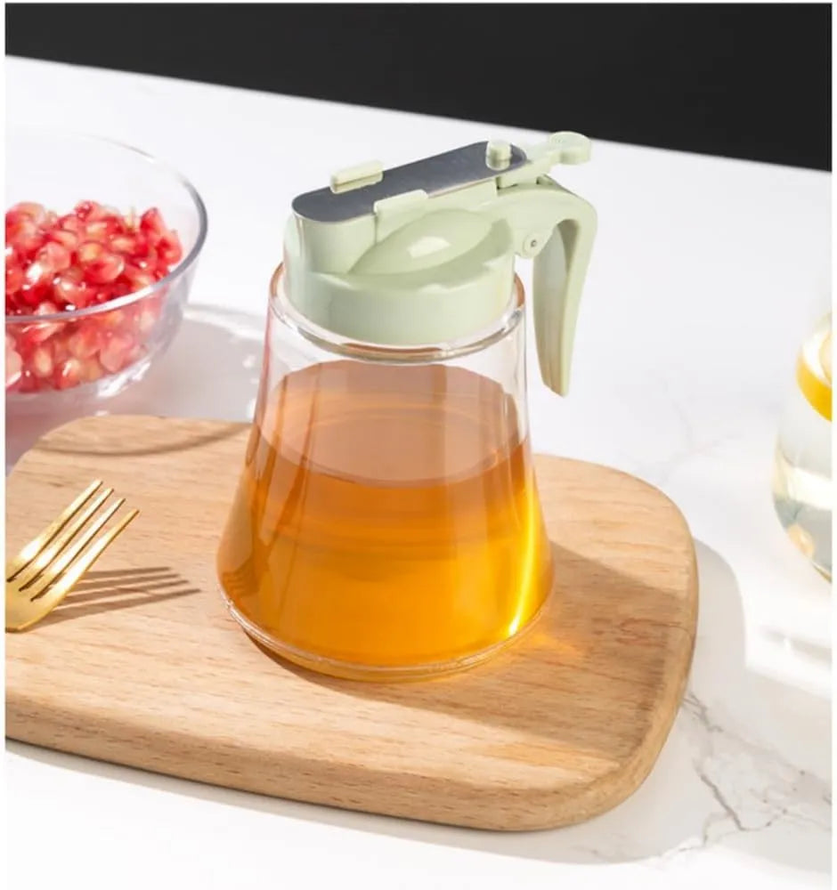 Glass container with a green lid on a wooden cutting board, surrounded by pomegranate seeds and a gold fork.