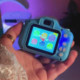 Toy camera with colorful screen held in a hand against a blurred background