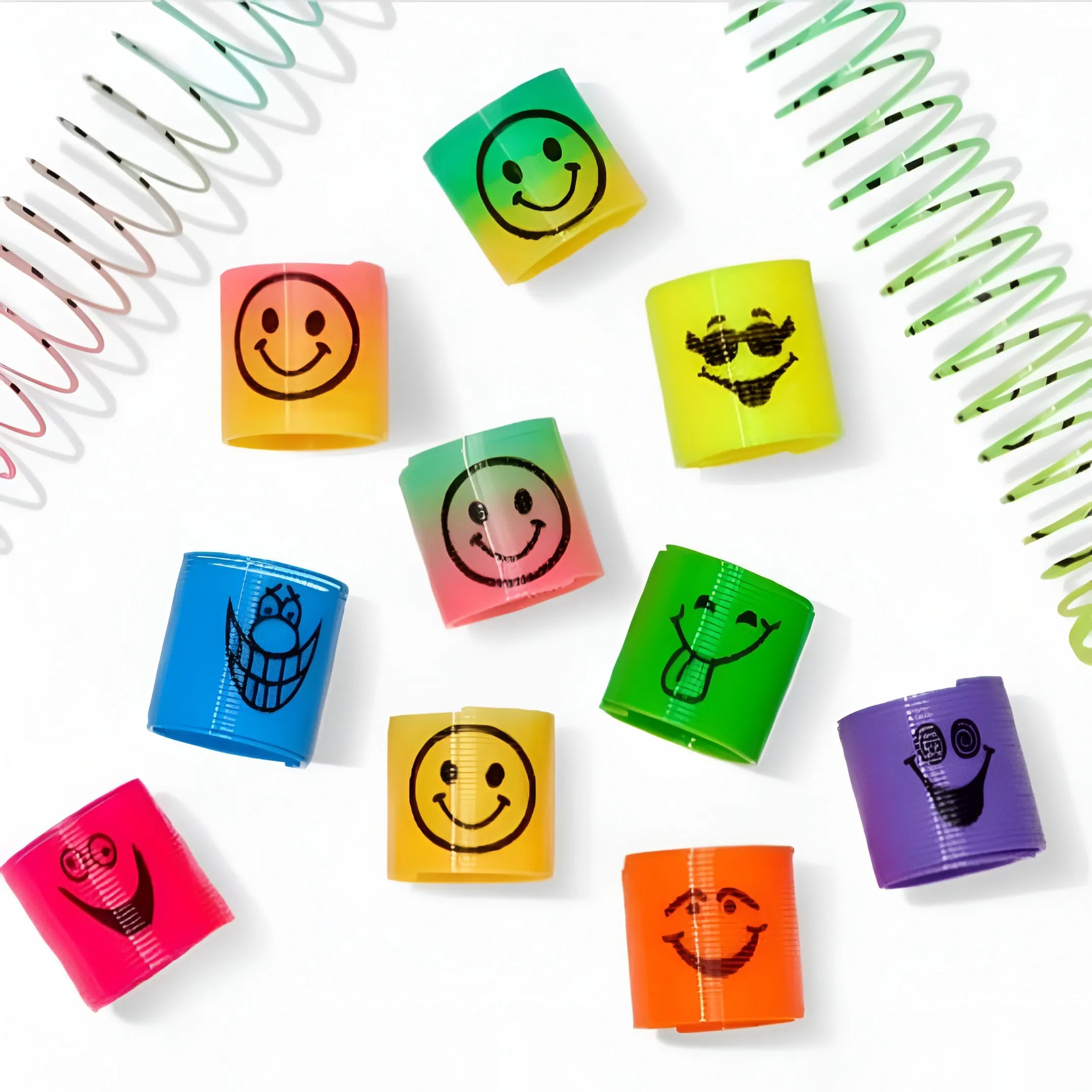 A set of colorful plastic twist-up wristbands with black cartoon smiley face designs, arranged on a white background with decorative spiral spring props.