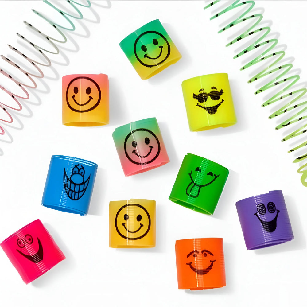 A set of colorful plastic twist-up wristbands with black cartoon smiley face designs, arranged on a white background with decorative spiral spring props.
