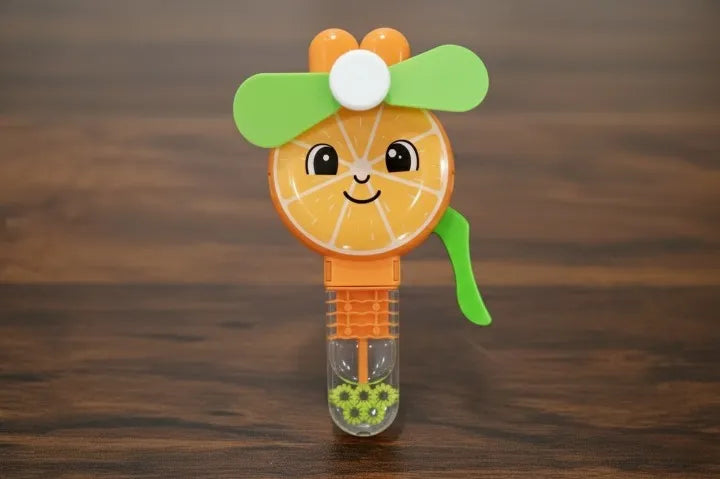 A cute orange-themed bubble wand with a smiling orange slice face, green propeller wings, and a clear bubble solution bottle on a dark wooden surface.