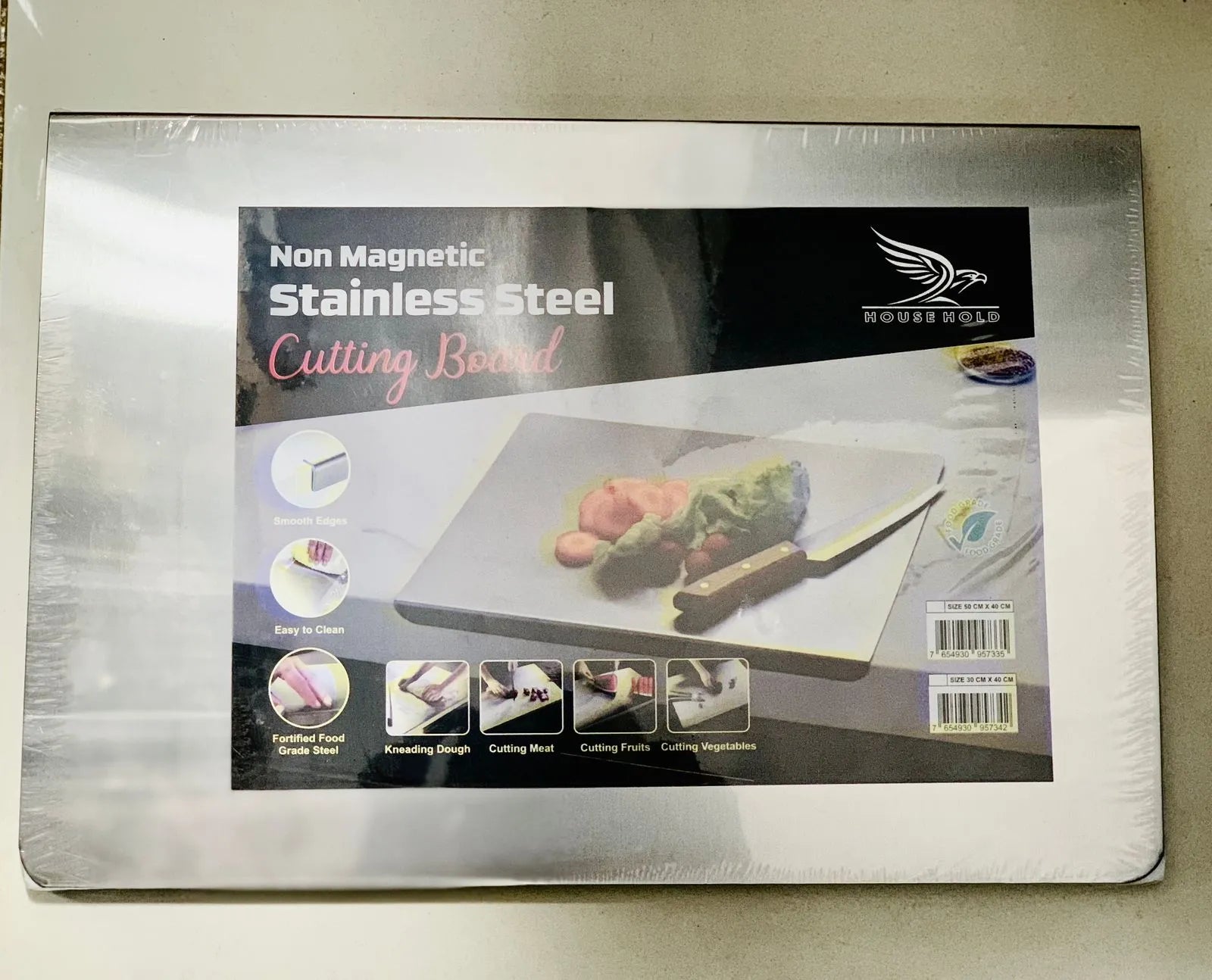 Non magnetic stainless steel cutting board in packaging on a light background