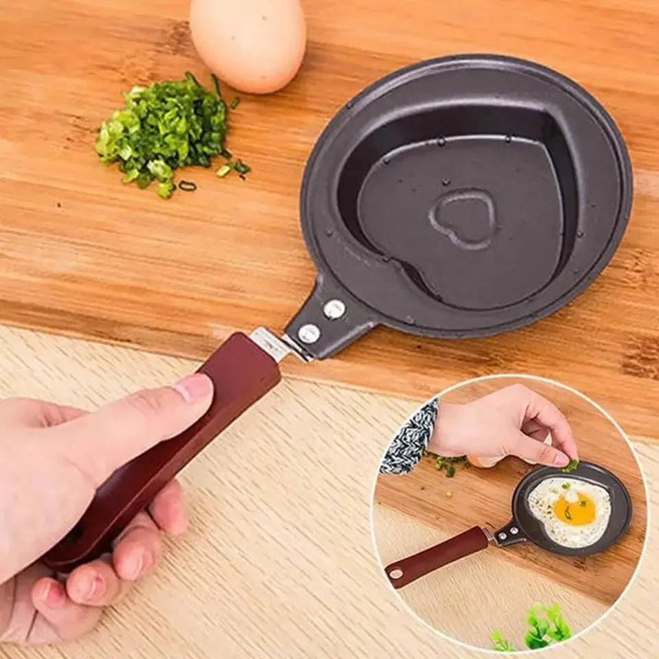 Small frying pan with a handle, used for cooking eggs on a wooden surface.