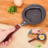 Small frying pan with a handle, used for cooking eggs on a wooden surface.