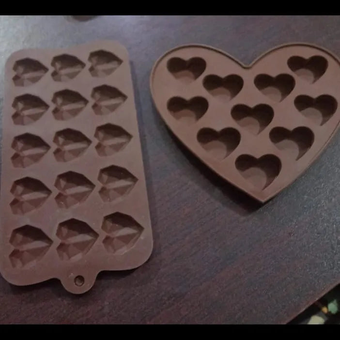 Two silicone molds with heart shapes on a dark surface
